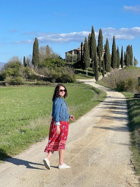 Woman walking on cypress lined road while in Tuscany with kids