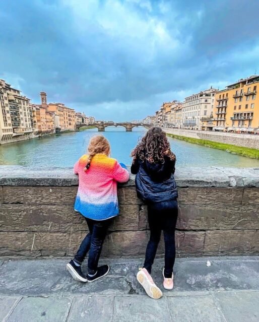 Two girls shot from behind looking at river in Florence while on a Tuscany family vacation photo credit: Adventurous Tastes