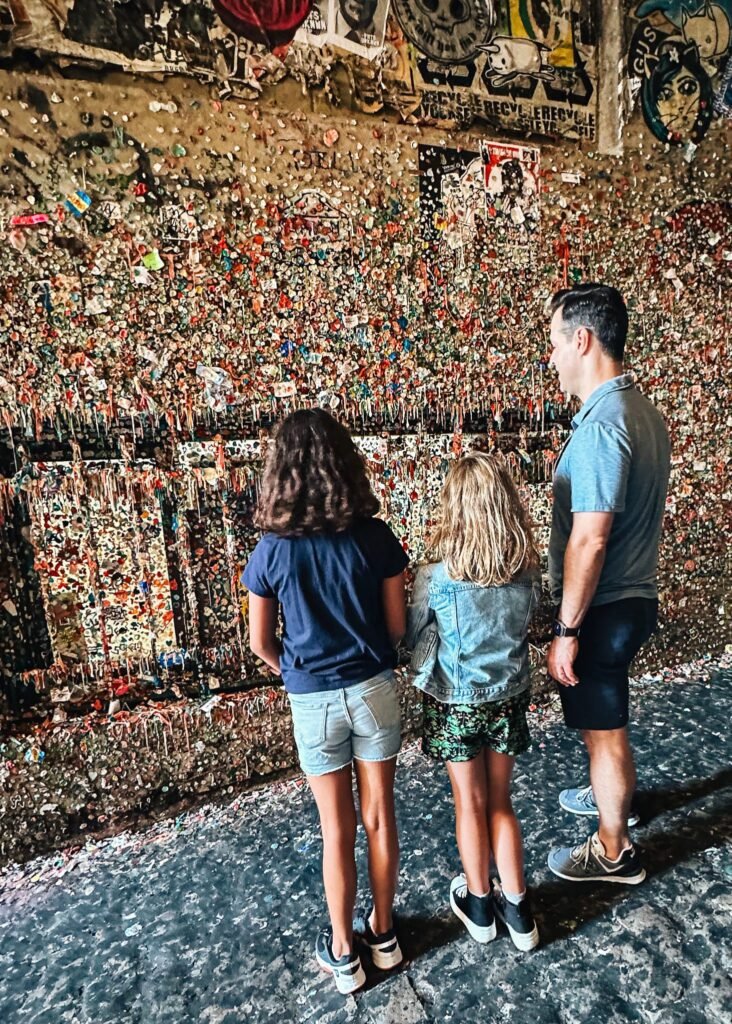 Man and two daughters looking at gum wall at Pike's Market in Seattle
