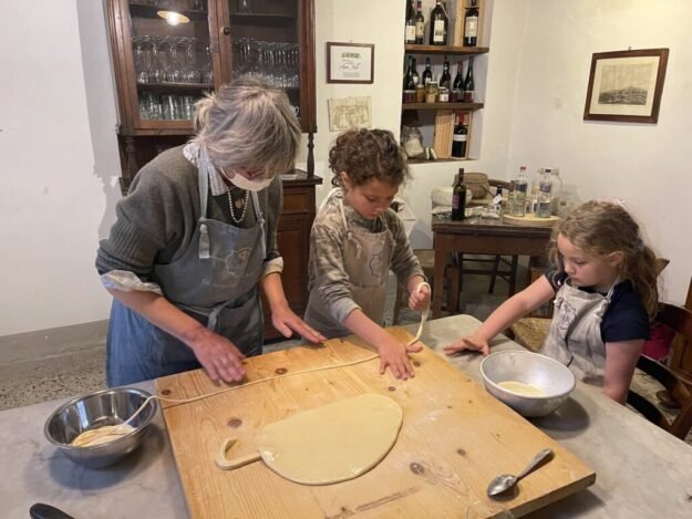 Two girls from Adventurous Tastes cooking with a nonna in Tuscany. This is a perfect activity for your trip to Italy