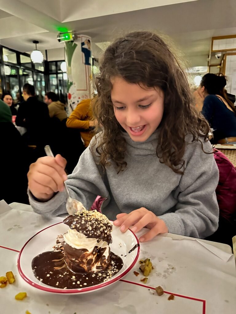 Dark haired little girl eating dessert at Bouillon Pigalle in Paris