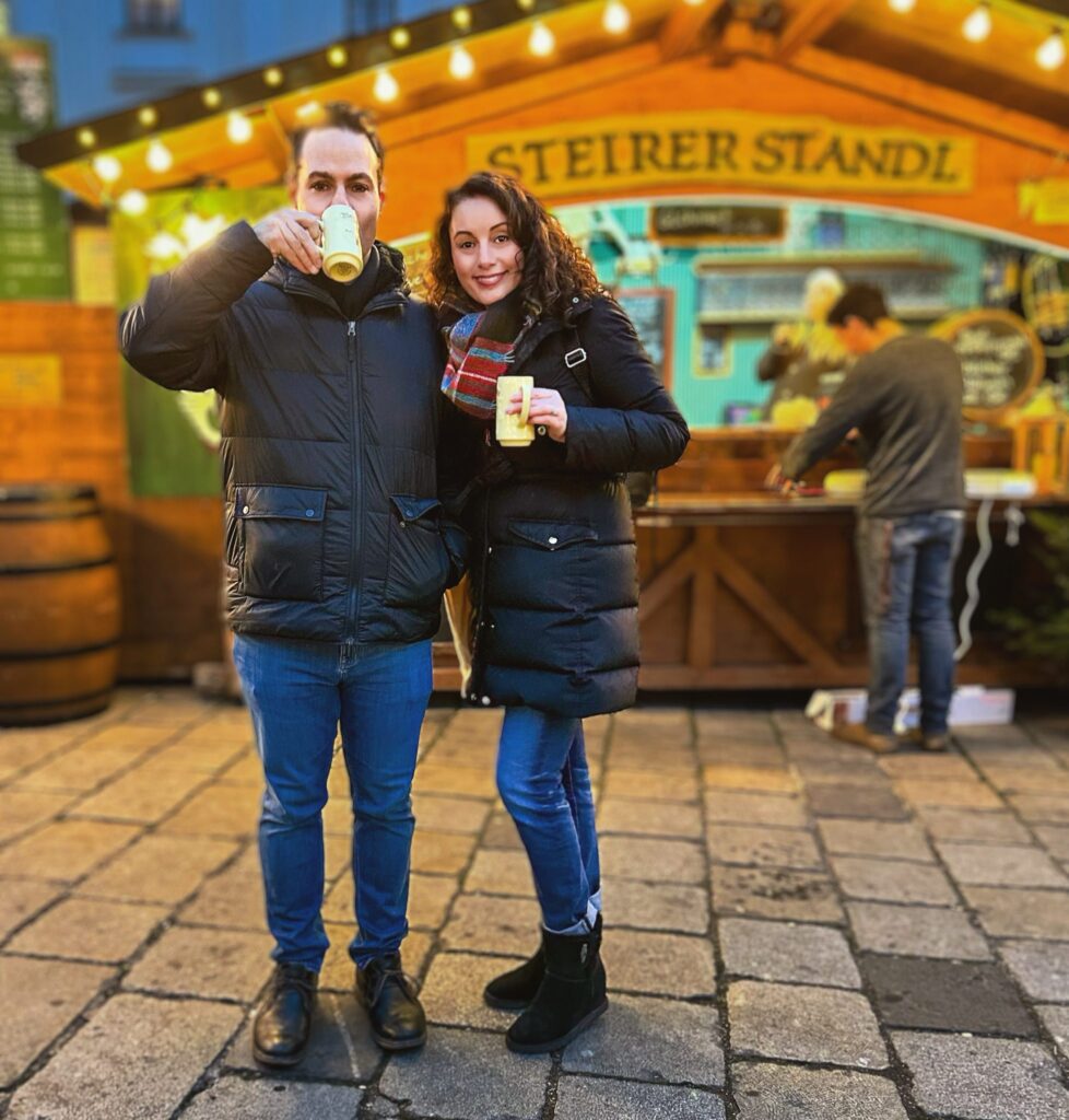 Man and woman drinking from mugs at Christmas market in Vienna, Austria