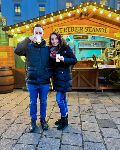 Man taking a sip of gluhwein with his wife by his side at Am Hof one of many lovely Austrian Christmas markets 