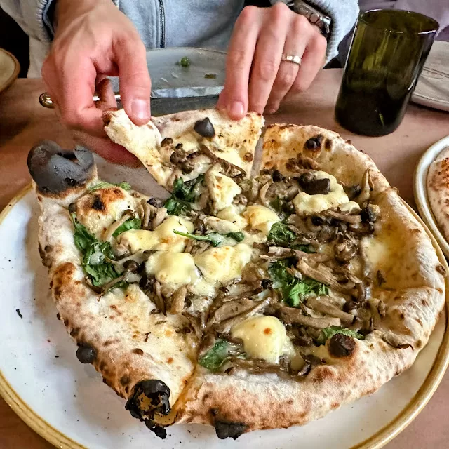 Close up of hands taking a slice of pizza a A16, a family-friendly restaurant in San Francisco, perfect when spending 4 days in Northern California with kids