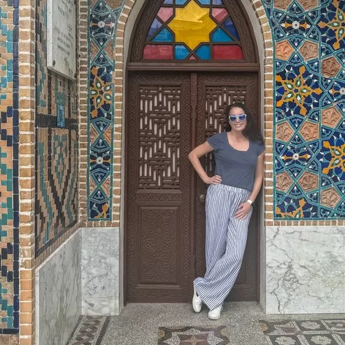 Woman leaning against a doorway in front of a mosaic tiled building in Tbilisi, Georgia