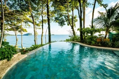 Arenas Del Mar - one of the besrt resorts to visit in Costa Rica with Kids. A pool looks out over the tropical beach near Manuel Antonio