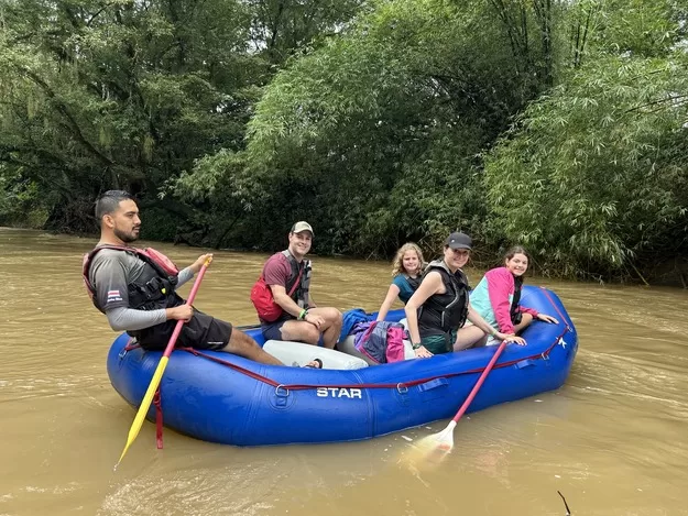 A safari float is a perfect family travel adventure near La Fortuna Costa Rica - family in a raft smiling on the water smiling for the camera 