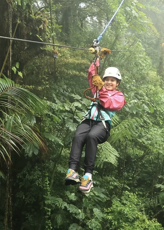 Adventure is a must when in Costa Rica with kids. Here a little girl ziplinines through the clouds in the cloud forests of Monteverde, Costa Rica