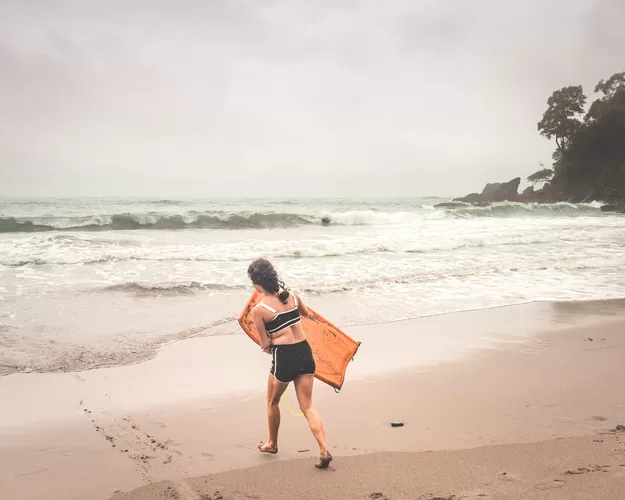 Girl walking with body board into the ocean near Costa Rica's Manuel Antonio Park | Costa Rica with Kids