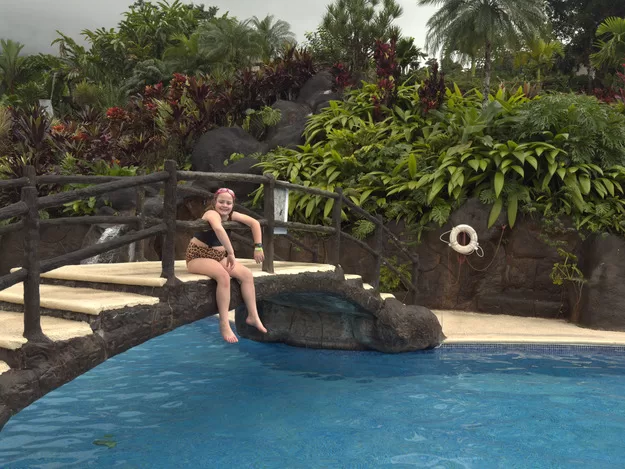 Little girl relaxing on a bridge at Los Lagos hot springs resort in Costa Rica - hot springs are one of the top things to do in Costa Rica