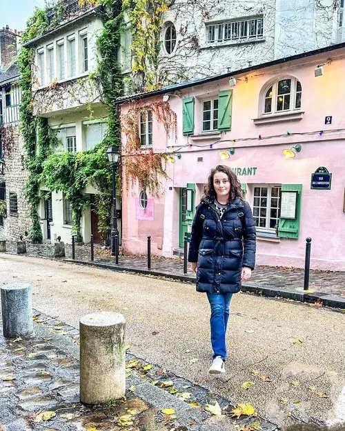 Woman in black parka walk on the prettiest street in Paris in Montmartre