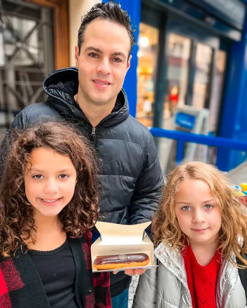 Man and two daugherrs holding an eclair in Paris